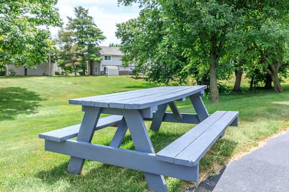 A blue picnic table and bench in a grassy area.