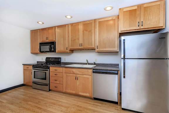A kitchen with wooden cabinets and a stainless steel refrigerator.