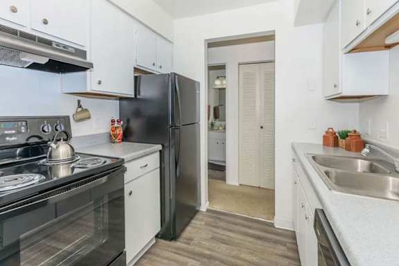 A kitchen with black appliances and white cabinets.