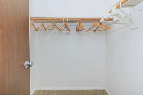 A white wall with a brown door and a coat rack with five hangers.