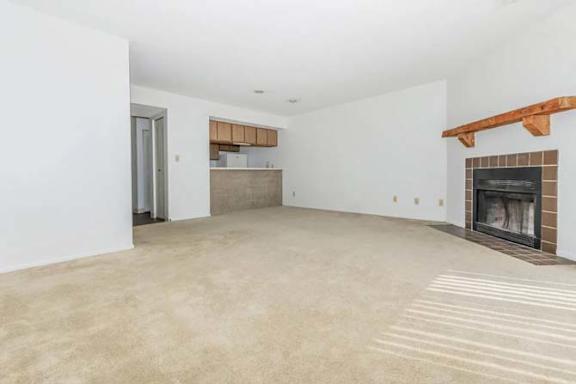 A spacious living room with a fireplace and a doorway leading to another room.