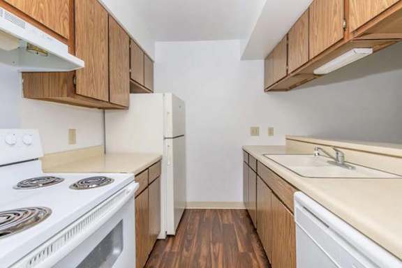 A kitchen with white appliances and wooden cabinets.
