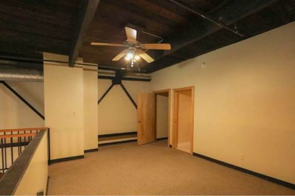 A room with a ceiling fan and a staircase.