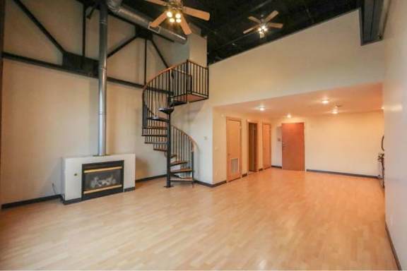 A room with a spiral staircase and a fireplace.