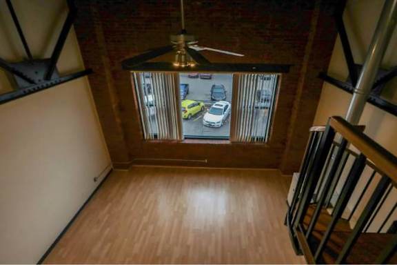 A view from the top of a staircase looking down at a car and a yellow car in a parking lot.