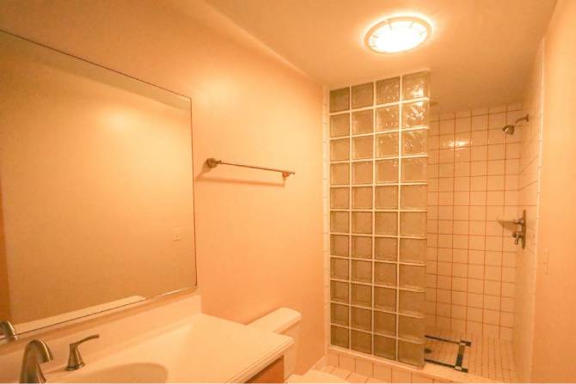 A bathroom with a white sink and a shower with a glass door.