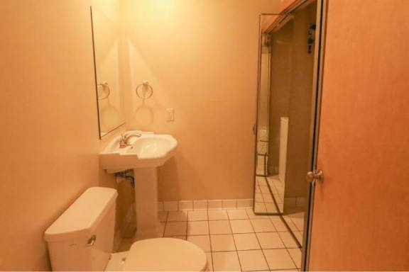 A bathroom with a toilet, sink, and mirror.