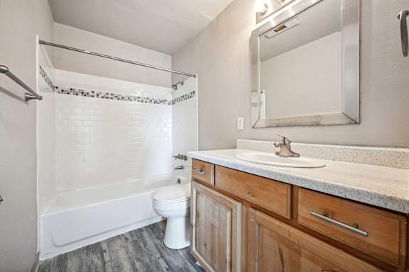 a bathroom with a toilet sink and shower and a mirror at Park at Fitzsimons Apartments, Colorado