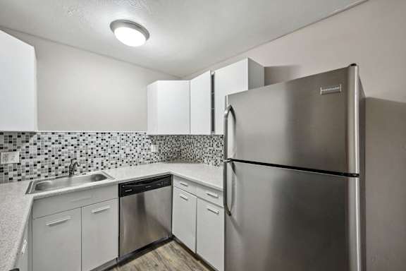 the kitchen has stainless steel appliances and white cabinets at Park at Fitzsimons Apartments, Aurora