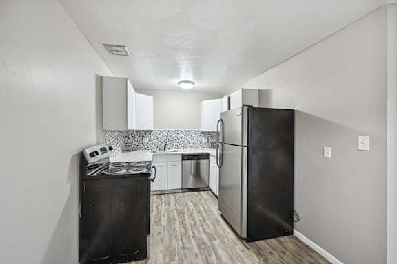 an empty kitchen with a refrigerator and a stove at Park at Fitzsimons Apartments, Aurora 80011