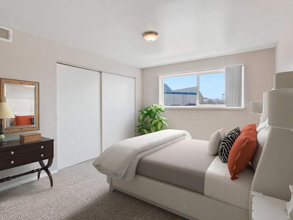 A bedroom with a bed, dresser, mirror, and a plant.
