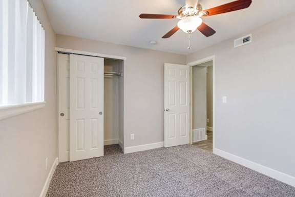 A room with a ceiling fan and carpeted floor.