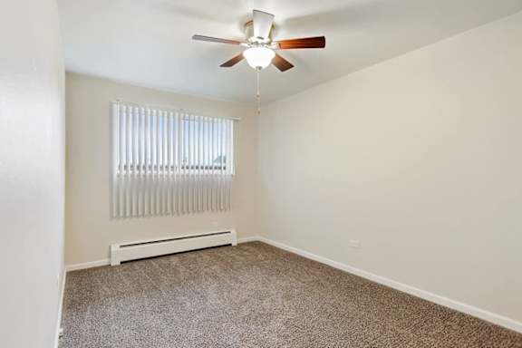 A room with a ceiling fan and a window with blinds.