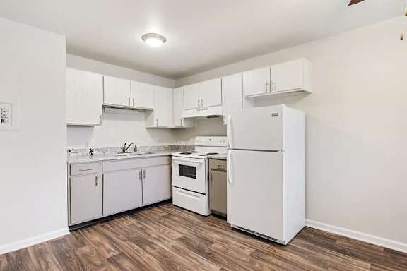 A kitchen with white appliances and wooden floors.