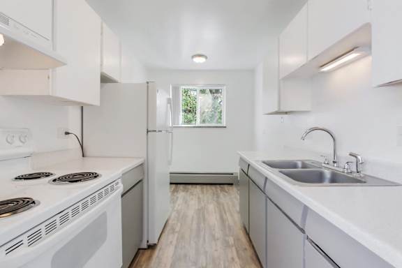 A white kitchen with a stove top oven and a refrigerator.