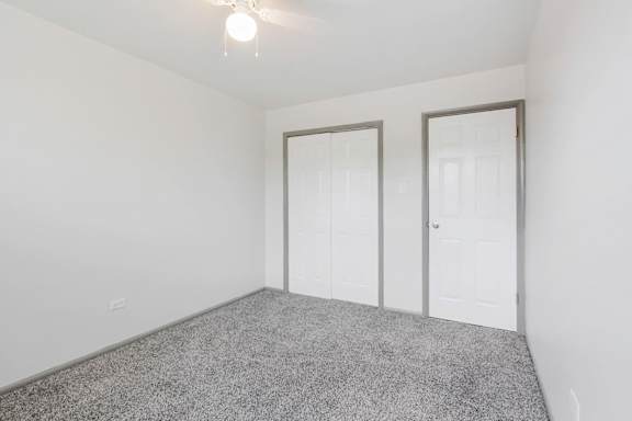 A room with a grey carpet and two white doors.