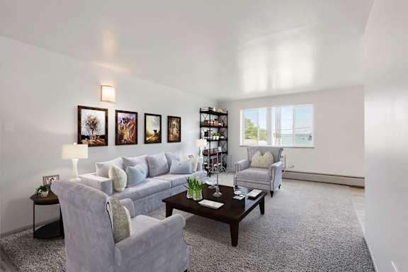 A living room with a grey couch, a grey armchair, a coffee table, and a bookshelf.