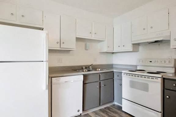 A white refrigerator is in a kitchen with white cabinets.