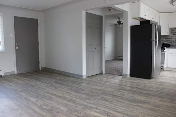 A kitchen with a black fridge and wooden floors.