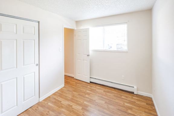 A white door is on the left of a room with a window and a radiator.