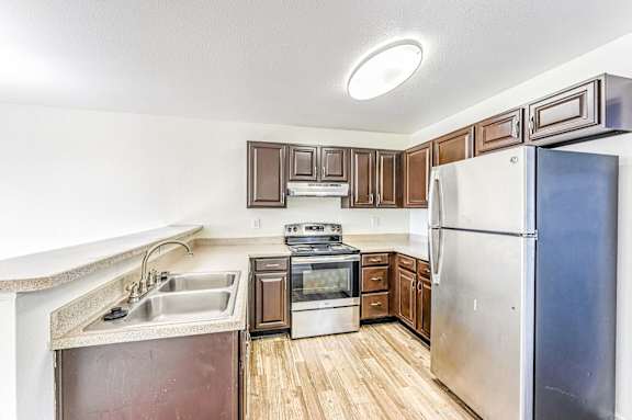 Kitchen with wooden closet and stainless steel appliances at Belle Creek Apartments, Henderson, Colorado