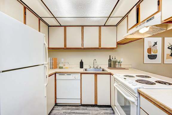 A kitchen with white appliances and wooden cabinets. at Autumn Village, Milton, WA, 98354