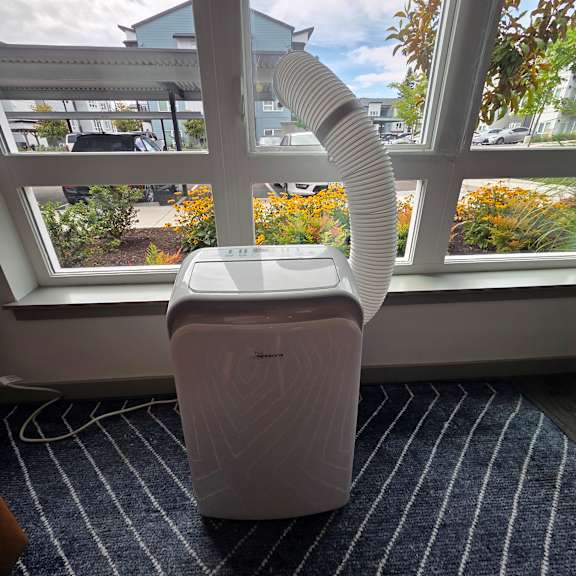 A white air purifier is on a windowsill.