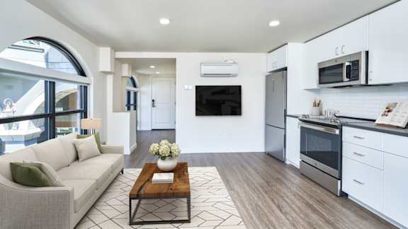 A modern kitchen with a breakfast bar and a living room area with a sofa.