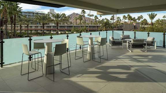 A patio with chairs and a table is set up on a balcony.
