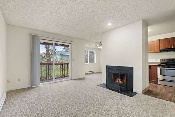 A living room with a fireplace and sliding glass doors. at Brookstone, Washington, 98198