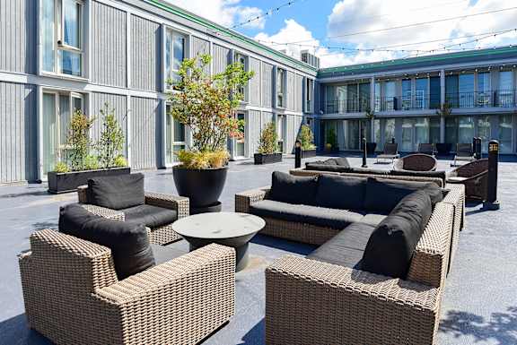 a patio area with couches and chairs and tables in front of a building  at Cosmopolitan, Seattle, WA, 98105