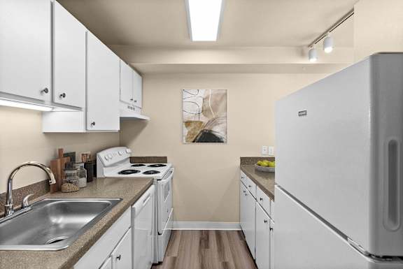 A kitchen with white cabinets and a white fridge.