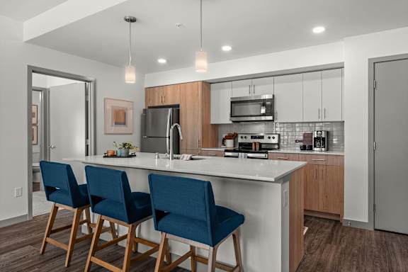 A kitchen with a white countertop and blue chairs.