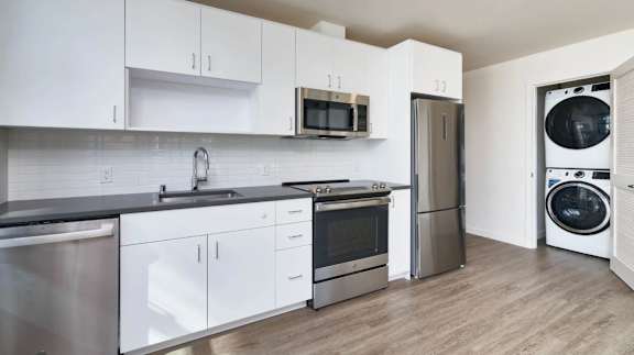 A modern kitchen with white cabinets and stainless steel appliances.