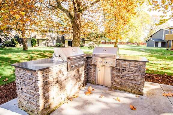 an outdoor kitchen with two stainless steel appliances on a stone wall
