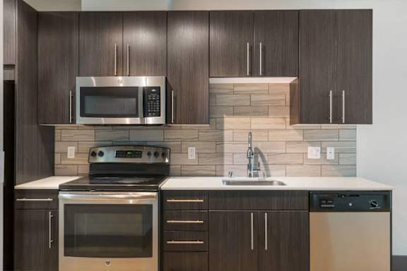 A modern kitchen with dark wood cabinets and stainless steel appliances.