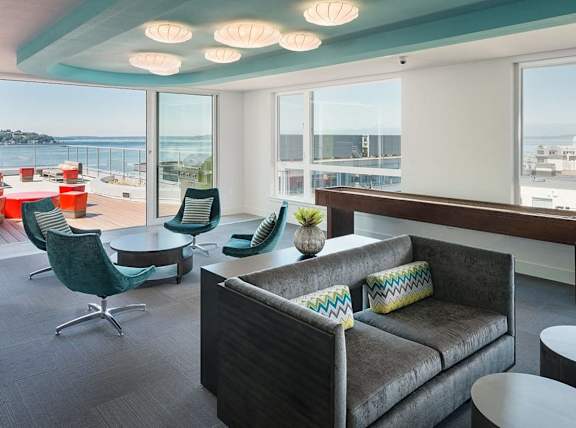 A living room with a couch, chairs, and a view of the ocean.