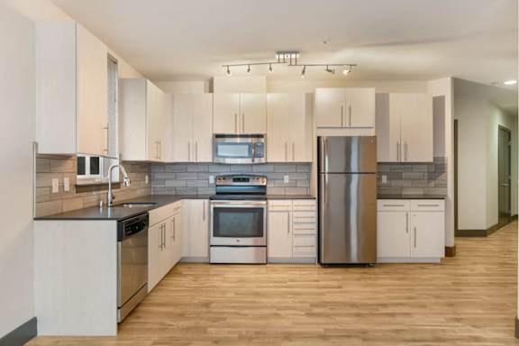 A modern kitchen with stainless steel appliances and wooden floors.