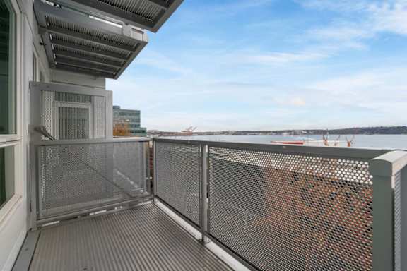 A balcony with a metal railing and a view of the city.