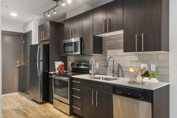 A modern kitchen with dark wood cabinets and stainless steel appliances.