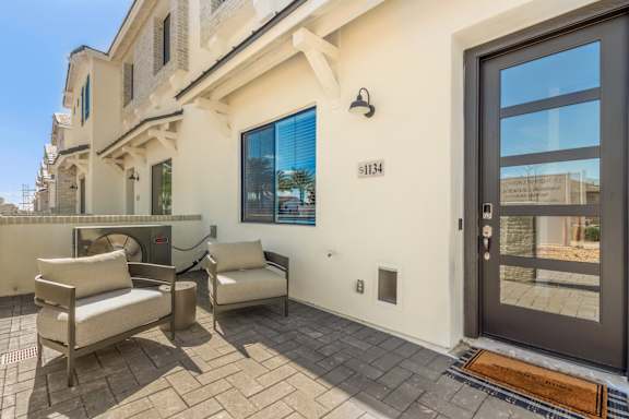 A modern house with a glass door and a balcony with two chairs.