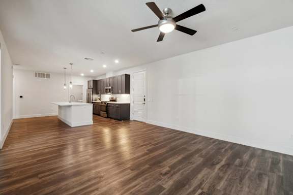A room with a ceiling fan and wooden flooring.