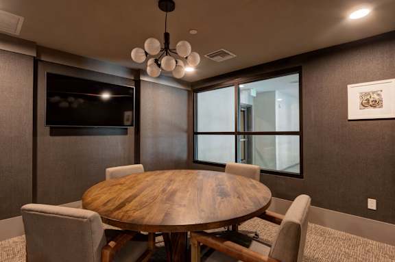 A modern conference room with a wooden table and chairs.