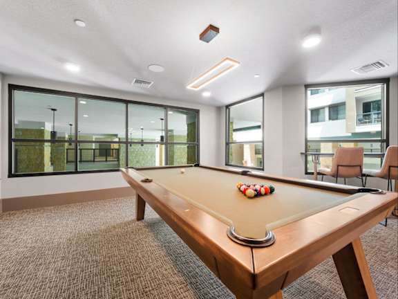 A pool table in a room with a brown carpet.