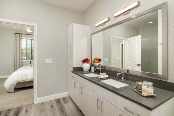 A bathroom with a large mirror, a sink, and a white chair.