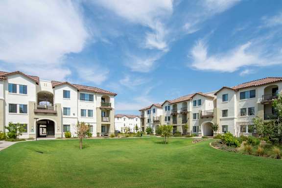 A row of apartment buildings with a green lawn in front.