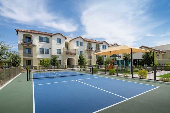 A tennis court is in front of a large building.
