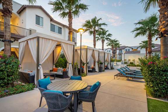 A patio with a table and chairs is surrounded by palm trees.