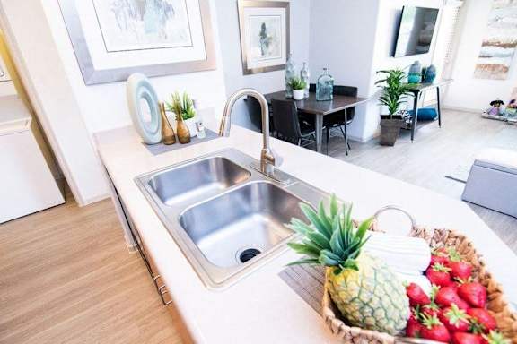 A kitchen with a sink and a fruit basket on the counter.
