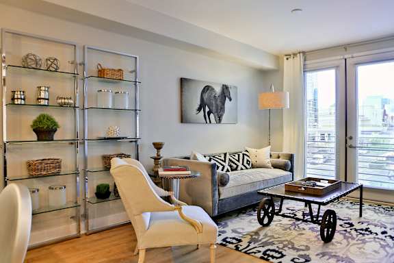 A living room with a glass shelf, a sofa, a chair, and a coffee table.